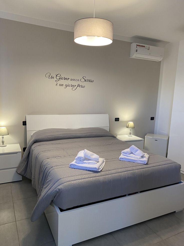 Camera con letto matrimoniale e arredi semplici, illuminata da una luce soffusa, creano un'atmosfera rilassante.