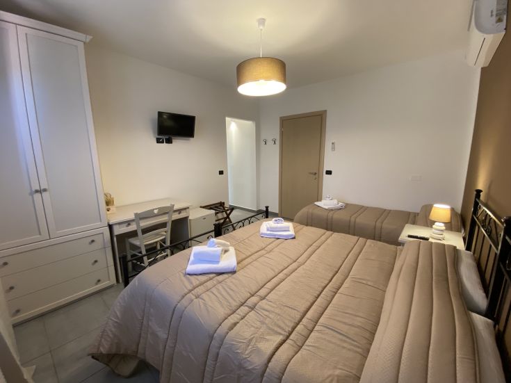 Stanza semplice con letti separati, un tavolo per scrivere e un televisore. Perfetta per un soggiorno tranquillo.
