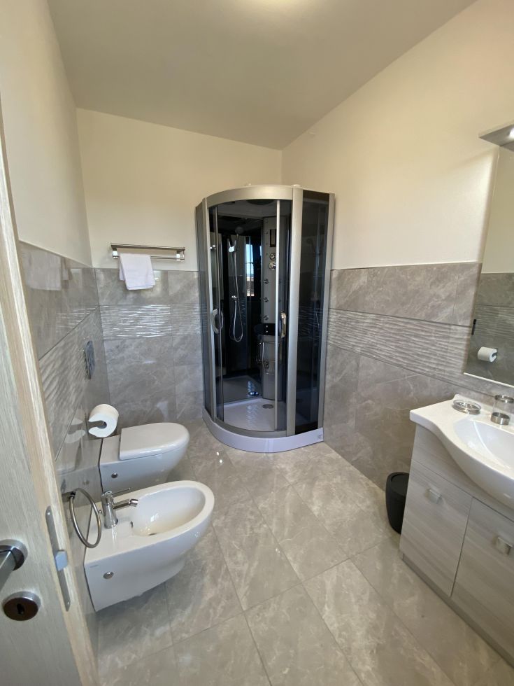 Bagno contemporaneo con doccia, wc e bidet, con piastrelle sobrie e di buon gusto.