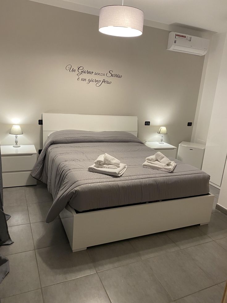 Spazio intimo con letto matrimoniale e decorazioni sobrie. Frase motivazionale su una delle pareti.