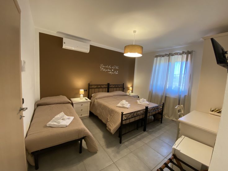 Una camera accogliente con letti singoli e matrimoniali, ben illuminata e arredamento semplice.