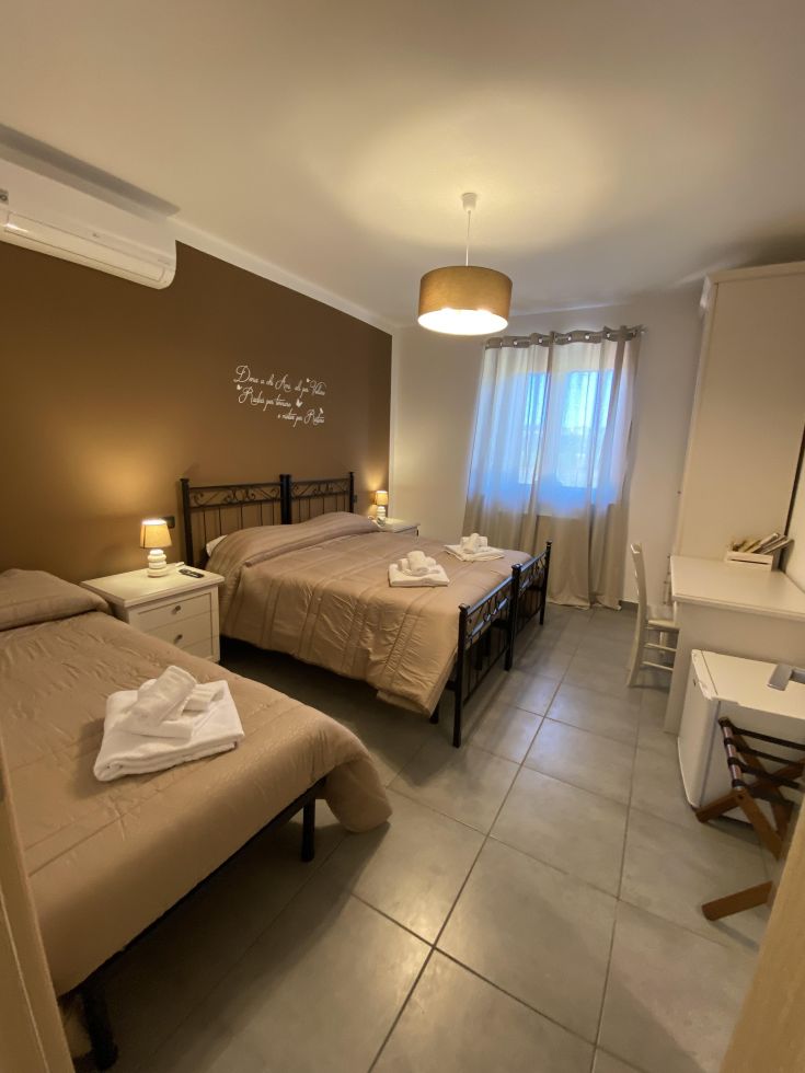 Stanza semplice con due letti singoli, arredata in modo funzionale e illuminata naturalmente.