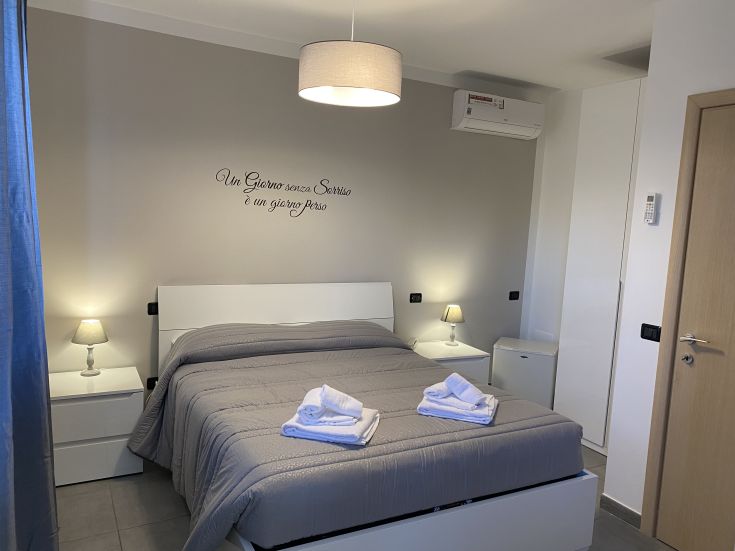 Ampia camera del B&B con letto matrimoniale, dotata di arredi semplici e decorazioni moderne per un soggiorno piacevole.