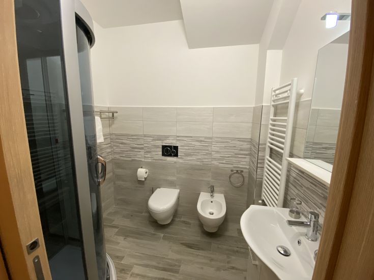 Ambiente di un bagno moderno, completo di doccia, bidet e lavabo, semplice e pratico.