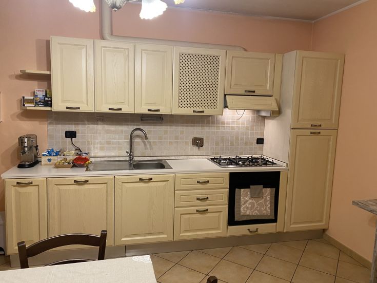 Cucina semplice e ben organizzata, con arredi di tonalità chiare e spazi funzionali.