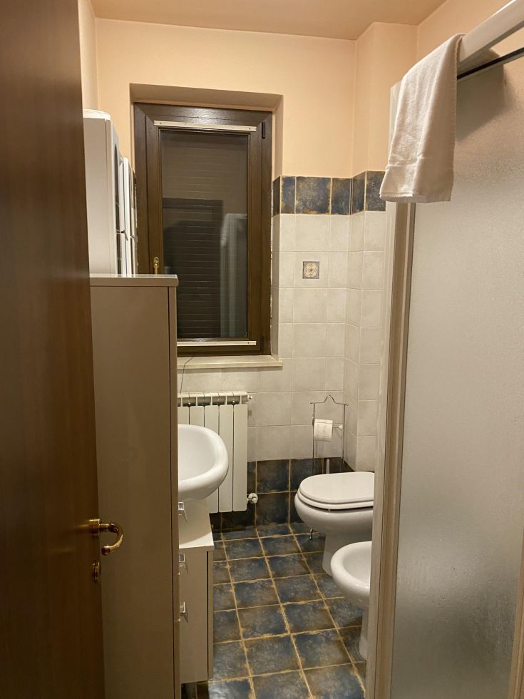 Un bagno semplice e funzionale dotato di rivestimenti in ceramica e una finestra per la luce naturale.