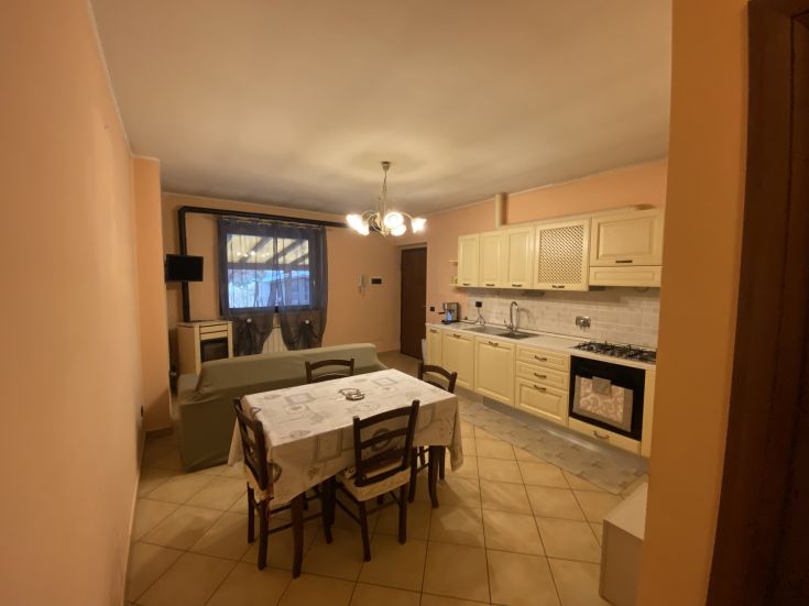 Cucina luminosa e accogliente con tavolo da pranzo, armadi in legno chiaro e ampie finestre.