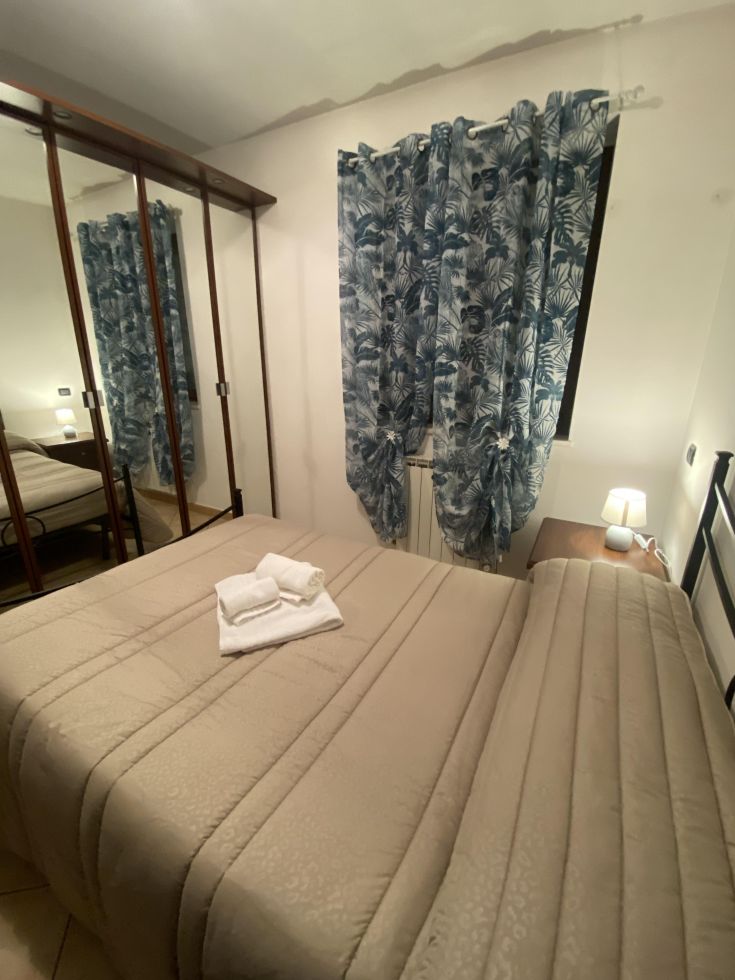 Una camera semplice con biancheria ben sistemata, tende con disegno e un'atmosfera tranquilla.