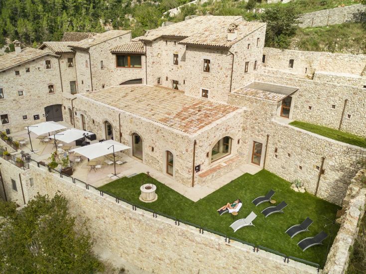 Un tranquillo panorama di un borgo medievale circondato da aree verdi, ideale per momenti di relax.