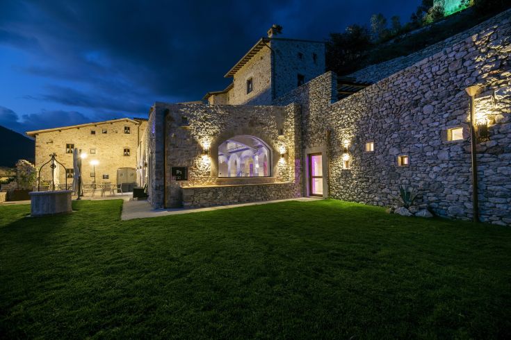 Un edificio storico immerso in un'area tranquilla, circondato da vegetazione e muri antichi.