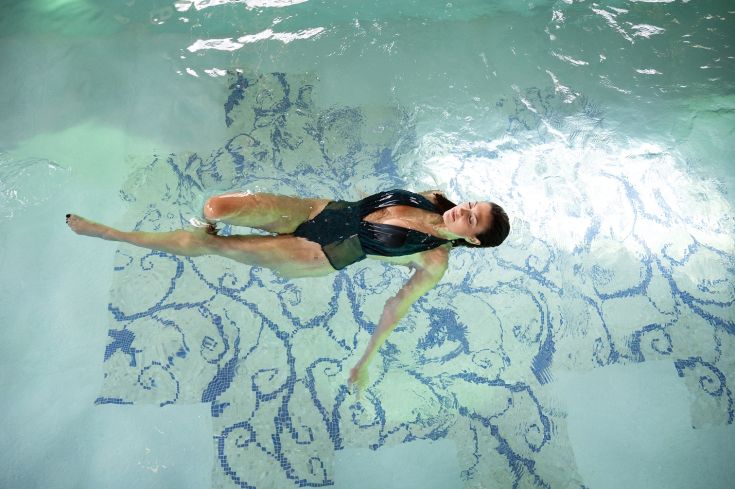 Una donna che si rilassa in un'ampia piscina, esprimendo un senso di calma e libertà.