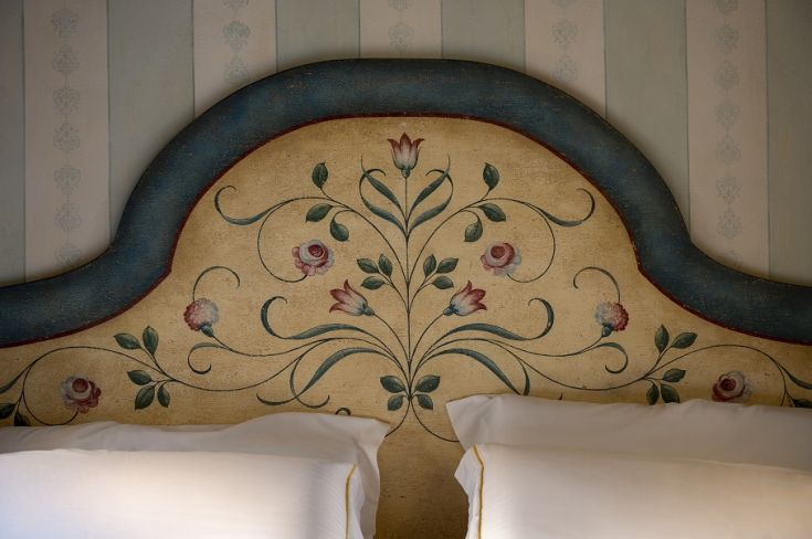 Testata del letto con semplici motivi floreali e colori tenui che si integrano bene nell'ambiente.