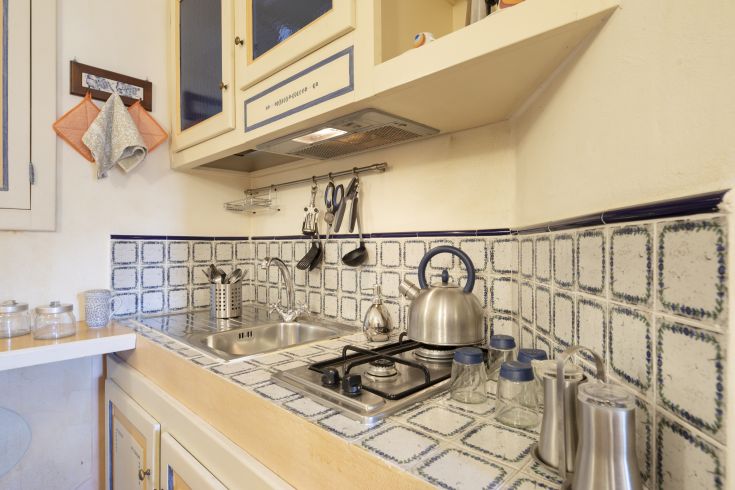 Cucina con piastrelle tradizionali e dettagli metallici, crea un'atmosfera calda e confortevole.