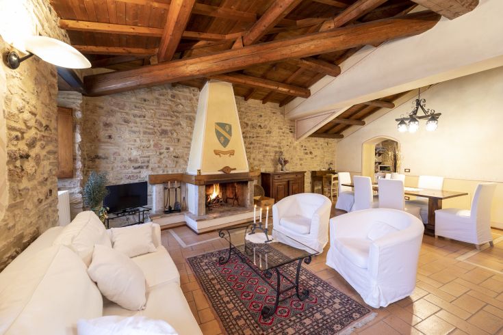 Un soggiorno confortevole con camino, travi in legno a vista e mobili in stile tradizionale. Ideale per momenti di relax.