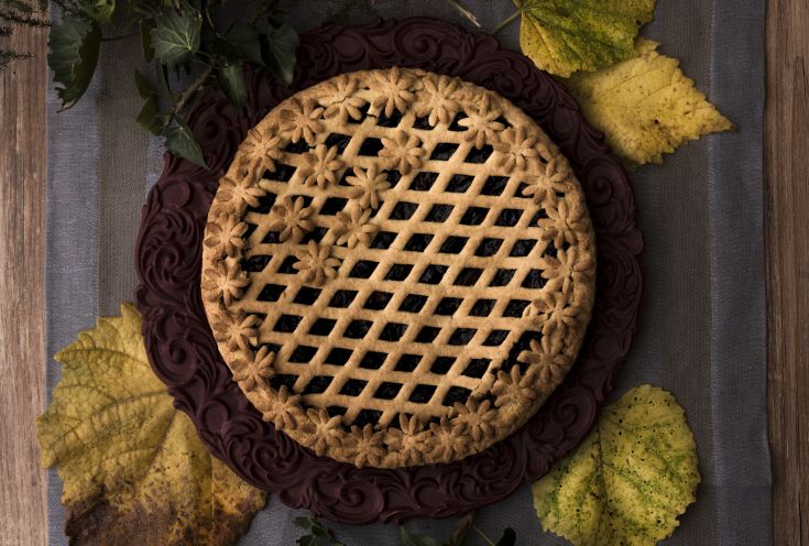 Torta con una decorazione a reticolo e fiori, presente su un tavolo in legno. Adatta per eventi e celebrazioni.