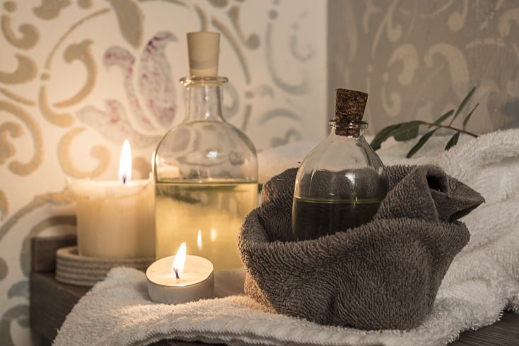 Ambiente tranquillo con candele, oli aromatici e asciugamani, tutto disposto in uno spazio confortevole.