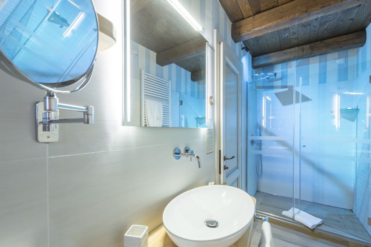 Un bagno contemporaneo con finiture semplici, doccia in vetro e specchio con illuminazione.