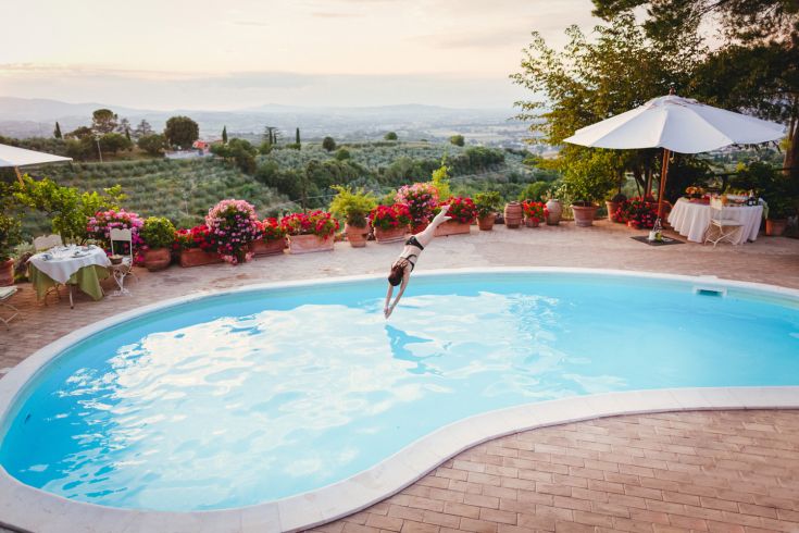 A dive into a swimming pool within a villa, surrounded by a relaxing natural landscape.