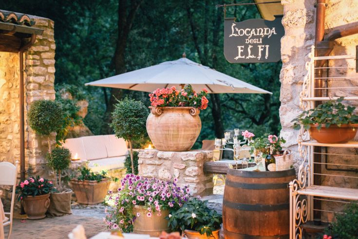 A simple inn surrounded by nature, filled with plants and flowers, perfect for relaxing moments.