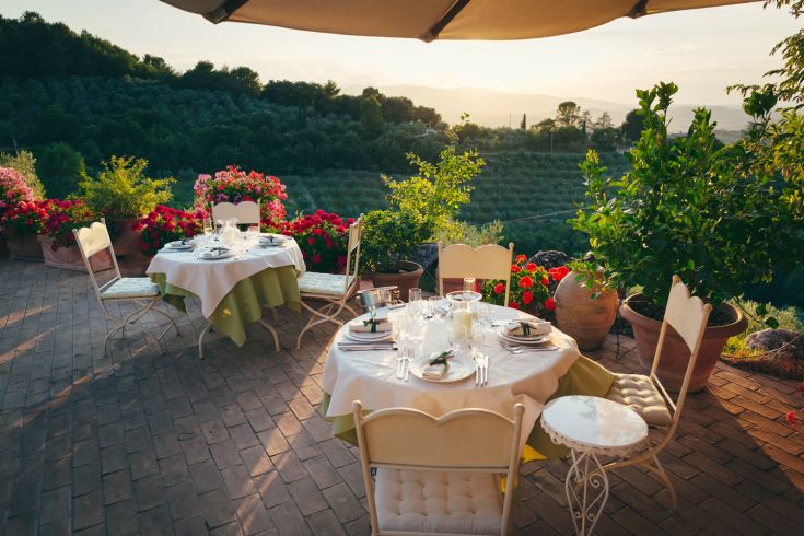 Outdoor restaurant with set tables and a view of the surrounding valley.