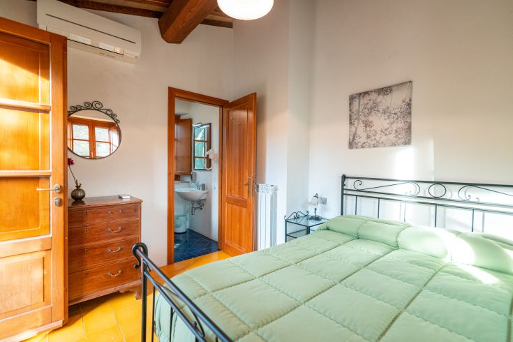 Geräumiges Schlafzimmer mit natürlichem Licht, ausgestattet mit einem Doppelbett und Möbeln aus hellem Holz.