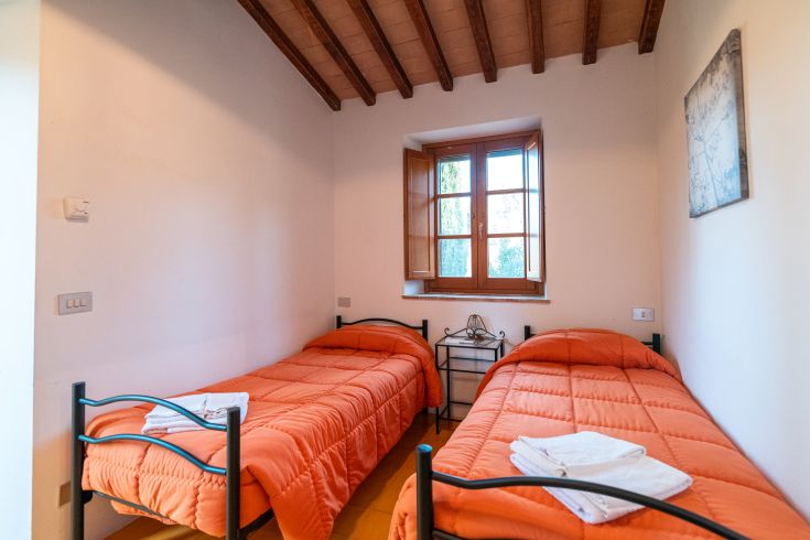 Funktionales Zimmer mit Einzelbetten und Blick auf einen Garten.