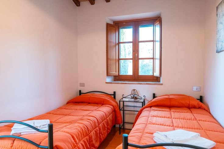 Einfache Kammer mit Einzelbetten und warmen Farbtönen, ideal für einen ruhigen Aufenthalt.