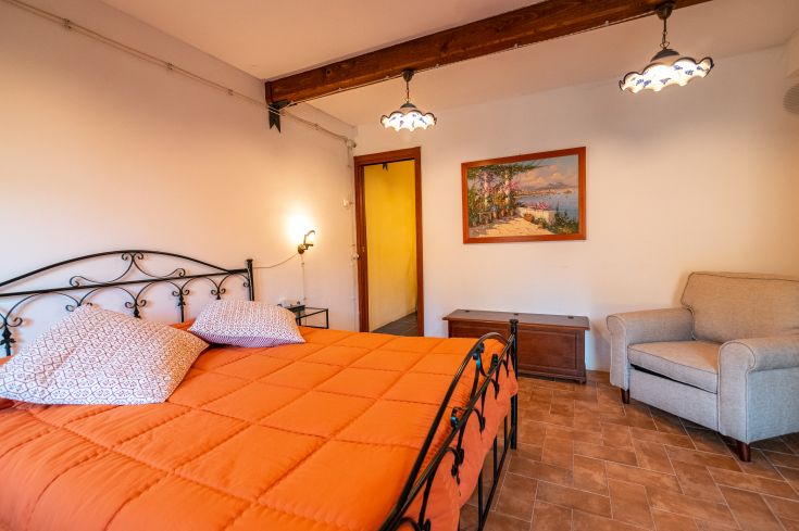 Ein einfaches Zimmer mit einem schwarzen Bett und orange Bettwäsche, beleuchtet von Vintage-Lampen.