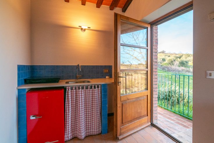 Eine gut organisierte rustikale Küche mit einem Bereich, der zum Garten im Freien führt.