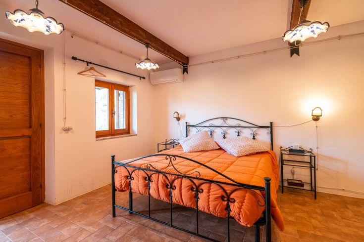 Geräumiges Schlafzimmer mit einem Doppelbett, einfacher Dekoration und viel natürlichem Licht.