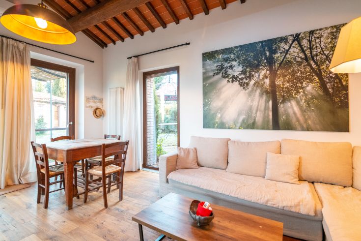 Gemütliches Wohnzimmer mit einem Holztisch und großen Fenstern für Tageslicht.