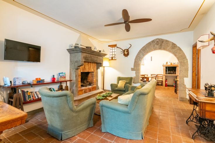 Geräumiges Wohnzimmer mit Kamin und rustikalen Elementen, ideal für entspannende Momente.