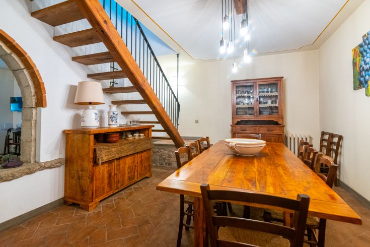 Innenraum des Palastes mit einem großen Tisch und einer gut erhaltenen Holztreppe.