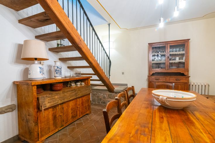 Innenraum eines Gebäudes mit Holzmobiliar, einer Treppe und einer schlichten, einladenden Atmosphäre.