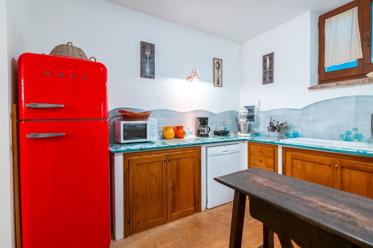 Einfache Küche mit rotem Vintage-Kühlschrank und rustikalen Elementen.
