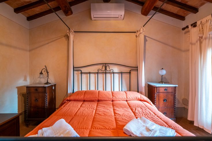 Gemütliches Zimmer mit einem orangefarbenen Bett und rustikalem Stil, ideal für entspannende Momente.