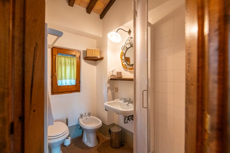 Funktionales Badezimmer in einem umbrischen Gebäude, beleuchtet durch Tageslicht mit Holzverkleidungen.