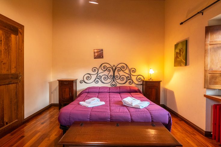 Ein einfaches Schlafzimmer mit einem Doppelbett und Holzmöbeln, ideal zum Entspannen.