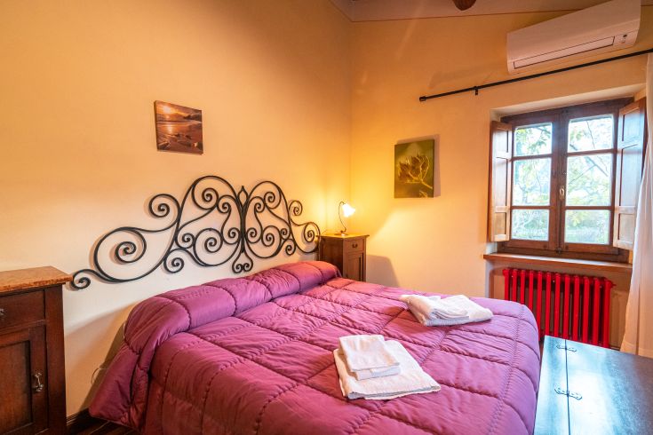 Einfaches Zimmer mit einem Doppelbett, warmen Farben und einer ruhigen Atmosphäre. Idealer Raum zum Entspannen.