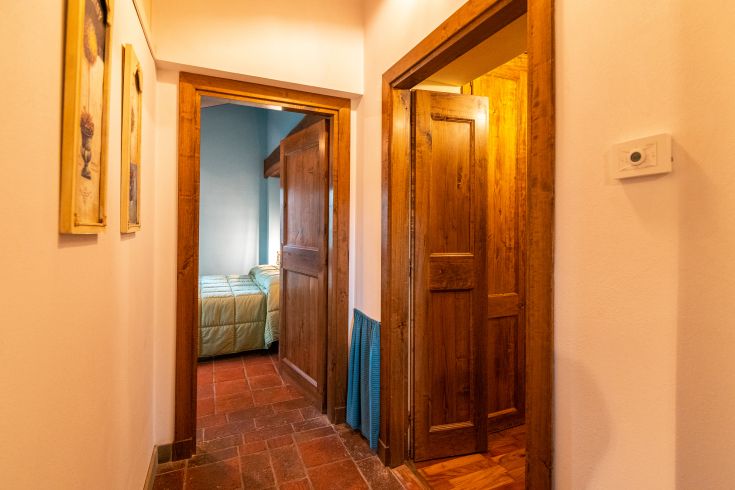 Einfacher Flur mit Holztüren, dekoriert mit Möbelstücken. Natürliches Licht, das den Raum erhellt.