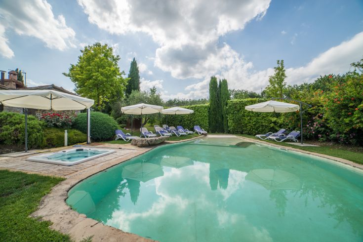 Ein ruhiger Pool, umgeben von üppigem Grün, Pflanzen und Blumen, bietet eine friedliche Umgebung zum Entspannen.