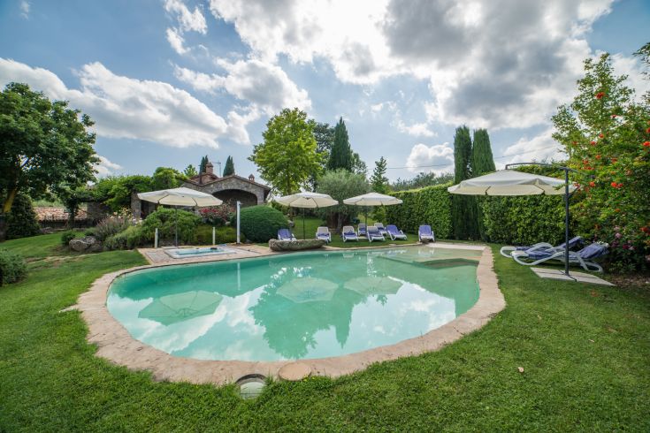 Entspannungsbereich in einer Villa mit Pool, umgeben von üppigem Grün.