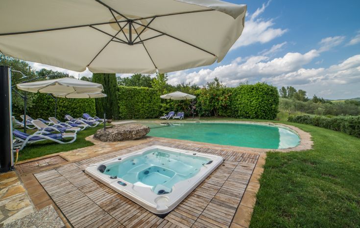 Außenbereich mit Swimmingpool und Whirlpool, umgeben von üppigem Grün.