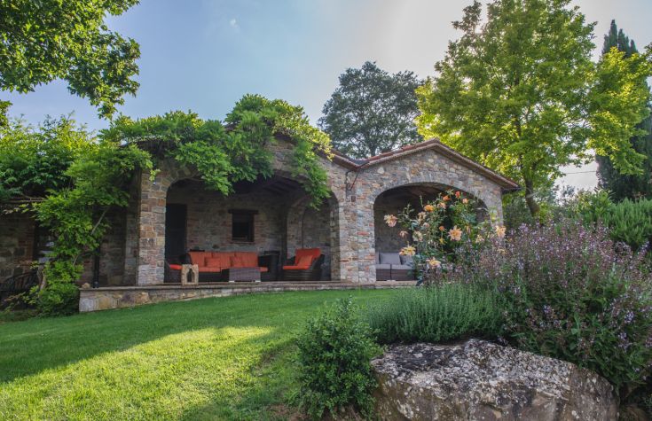 Ein Landhaus in einer grünen Umgebung, das Außenbereiche bietet, die ideal zum Entspannen und Geselligkeit sind.