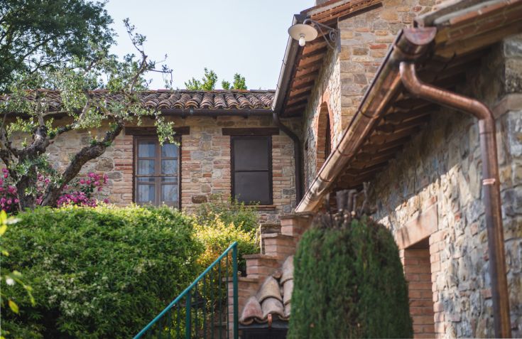 Szene eines typischen umbrischen Bauernhauses, umgeben von üppigem Grün und Bäumen.