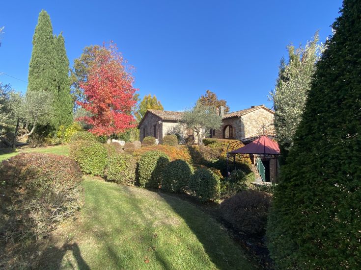 Ein gemütliches Landhaus umgeben von üppigen Gärten und bunten Bäumen.