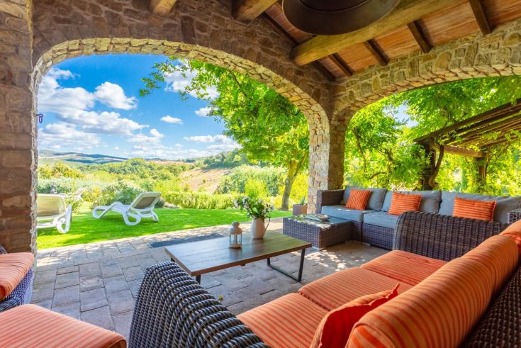 Eine ruhige Szene von einer Veranda mit bequemen Stühlen und einem gepflegten Garten.