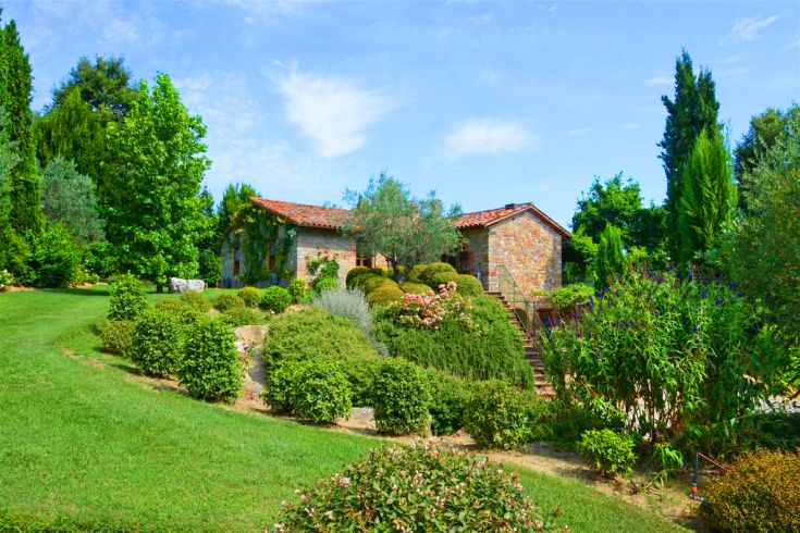 Ein Gebäude, umgeben von Bäumen und bunten Blumen in einem grünen Bereich.