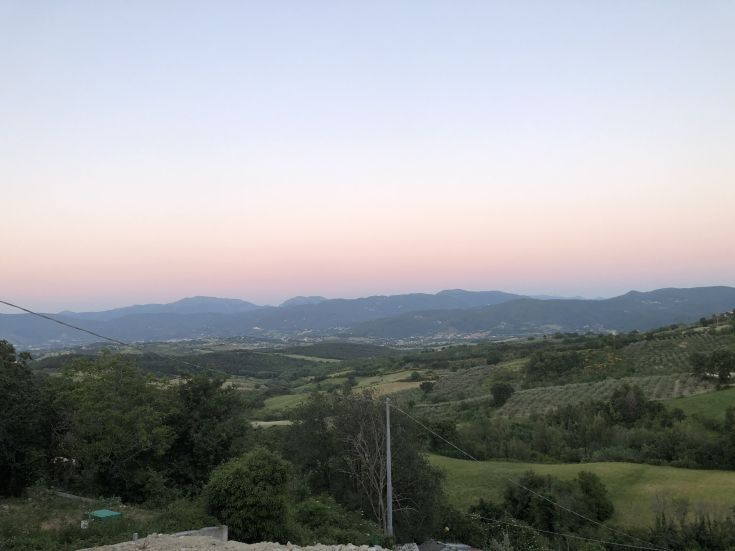 A peaceful countryside scene with gentle hills and sunset sky colors.