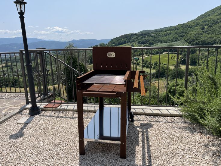Outdoor space equipped for barbecues, overlooking a green valley.